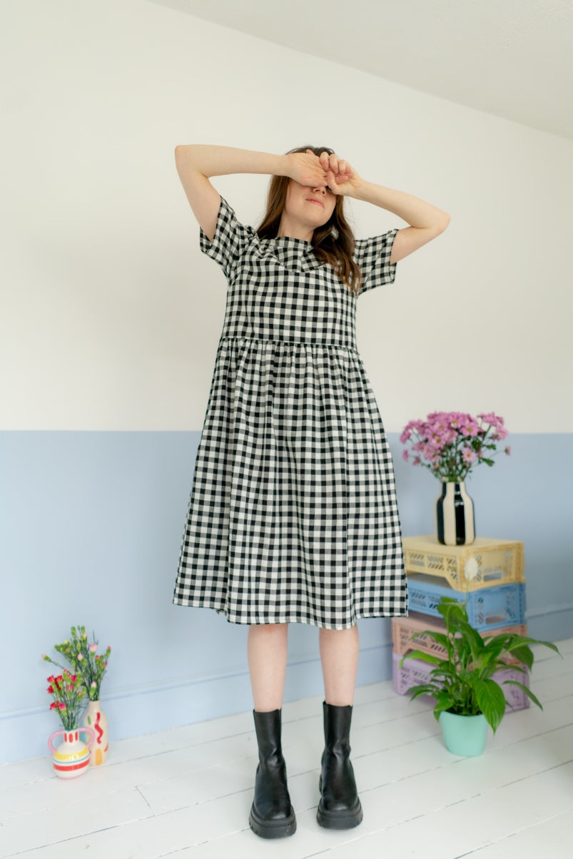 woman wearing ethical black and white gingham dress surrounded by houseplants